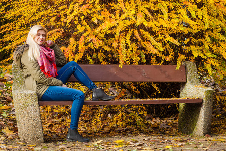 放松在秋天公园的长椅上坐着的女人