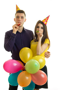 性格开朗的年轻夫妇，在生日聚会上吹着号角的垂直肖像