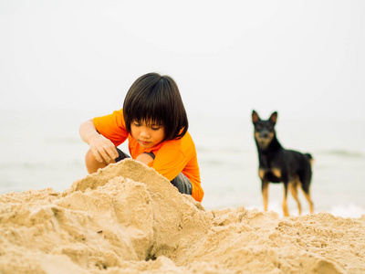 快乐的孩子享受与制作砂城堡和山在热带海滩