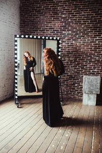 在靠近镜子黑色礼服的女人图片