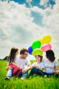幸福的家庭，坐在室外的一个温暖的夏日的汽球