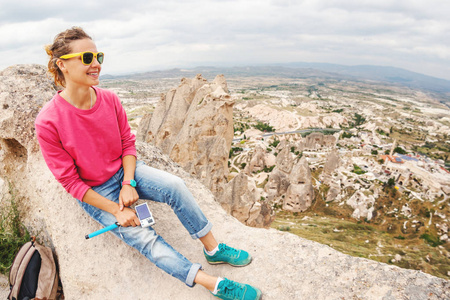 年轻快乐的女人旅行用相机在一座山上