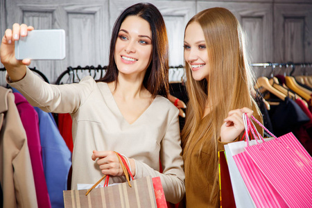 知足令人愉快知足的年轻女孩在购物中心购物,按住包使自拍照照片