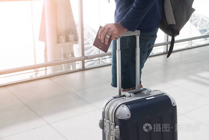 男人拿护照和行李行李箱在机场的特写