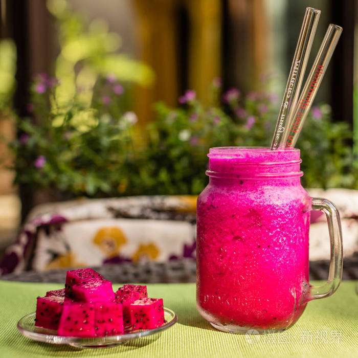 红龙在两个玻璃吸管 切的火龙果在一块玻璃板上一杯果汁 在背景上的花 绿色织物表面 侧面图 方形图像照片 正版商用图片014jwd 摄图新视界