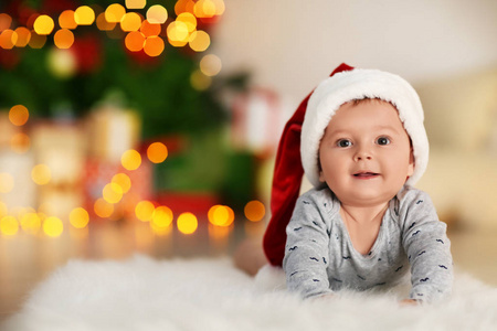 可爱的小宝宝趴在地板上, 对模糊的圣诞灯