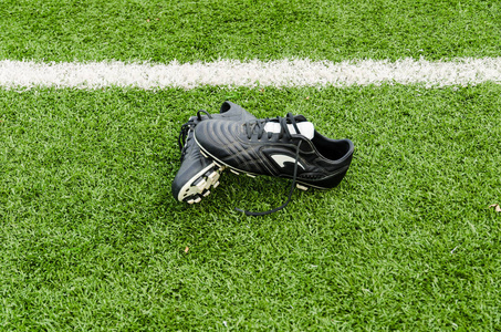 足球球和鞋子在绿色的草地上