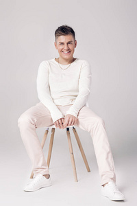 英俊的年轻男子，在白色的毛衣坐在一张椅子