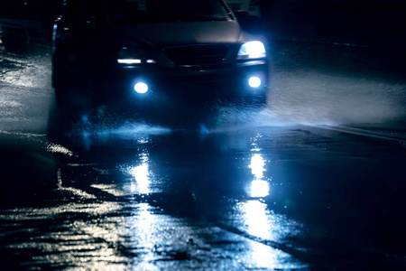 在雨夜中行驶的汽车.模糊的蓝色车灯照片