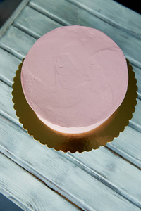 粉红色的蛋糕是完美的形状, 覆盖着奶油.在看台上.不装饰, 冷冻后照片