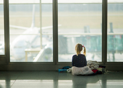 小女孩坐在一个大的窗口，在机场附近