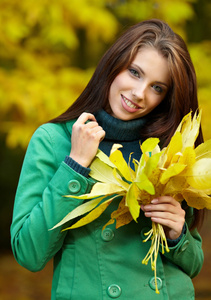 秋天公园里拿着黄叶的时尚女人