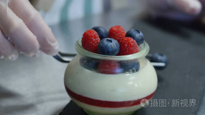 自制酸奶蓝莓在一个玻璃瓶中。把草莓酸奶中的手