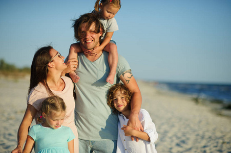大幸福的家庭在海滩漫步。妈妈, 爸爸和三孩子。蓝天阳光清新的海风。自然与交流的愉悦