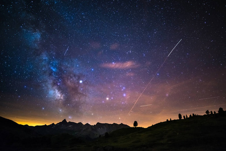 多彩发光的核心银河和满天星斗的天空，在对意大利的阿尔卑斯山，都灵省夏季在高空捕获。在天空中的飞机交通