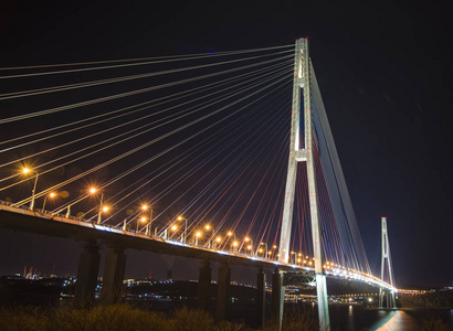 美丽的夜晚城市的灯光。高大桥横跨海湾伸展在塔上