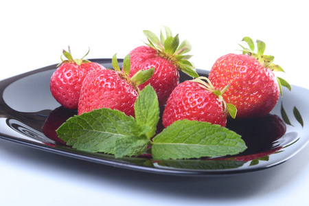 新鲜草莓和薄荷叶在黑版上。选择性的焦点