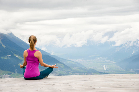 年轻女子打坐在山顶照片