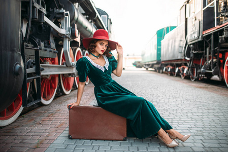 女人坐在行李箱逼平蒸汽火车上图片