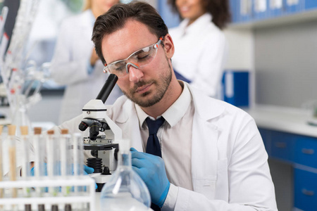 科学家通过显微镜在实验室里做研究实验的男性研究员照片