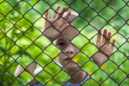 抽象图片链链接围栏身后的小男孩。照片