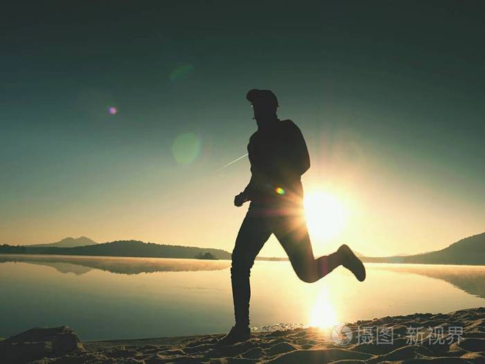 男孩在用反射日出期间在沙滩上跑.晴朗的天空早上湾海滩