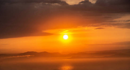 明亮的夕阳红着海上的暴风雨之后。水和大量云层的猩红色落日