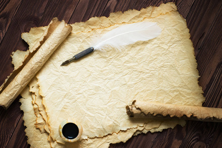 纸卷轴用羽毛笔和墨水壶木背景照片