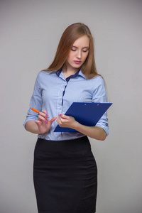 年轻美丽的商业女性是持有文档 tablet 和笔，是一个灰色背景思考