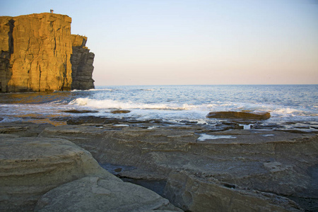 力量的磐石，折叠在蓝色的大海，与太阳眩光，雄伟壮观的岩石