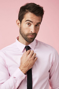 伙计在粉红色的衬衫调整领带