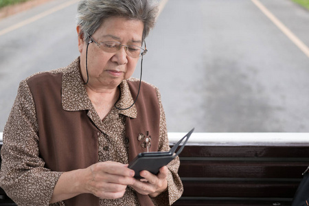 亚洲老女人坚持总线的智能手机。老人森