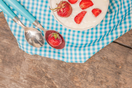 在一杯酸奶和新鲜的草莓，在蓝色的勺子毛巾上