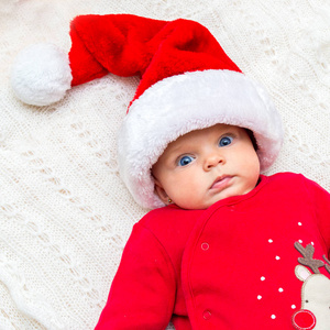 小女婴在圣诞老人的帽子，她看着相机