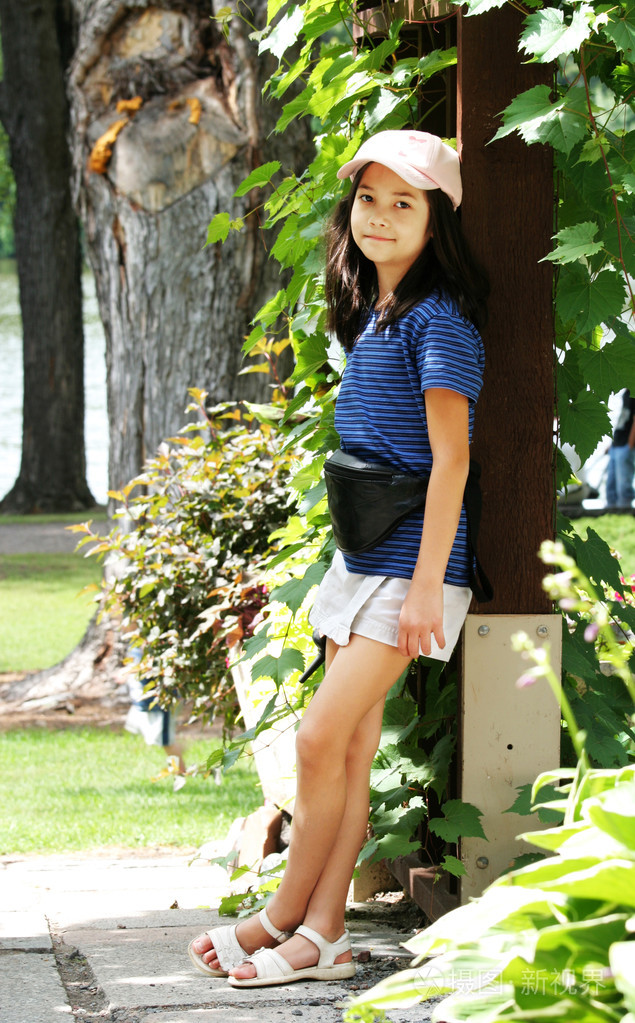 八岁的女孩躺在覆盖的乔木下休息