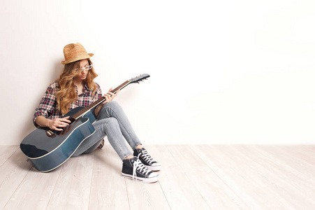 美丽的女人坐在一起坐在木地板上她吉他