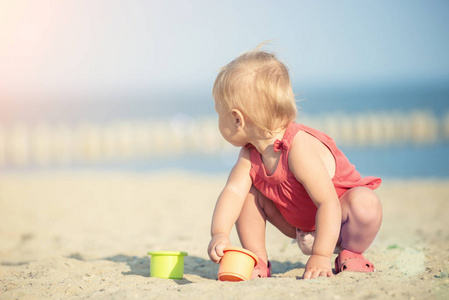宝贝女孩穿着红色在海边的沙滩上玩