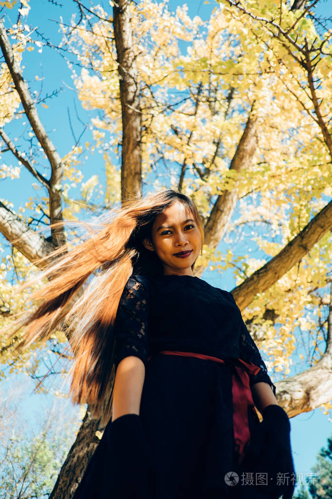 幸福的年轻女人在阳光明媚的秋日公园内微笑性格开朗的美丽女孩在黑色