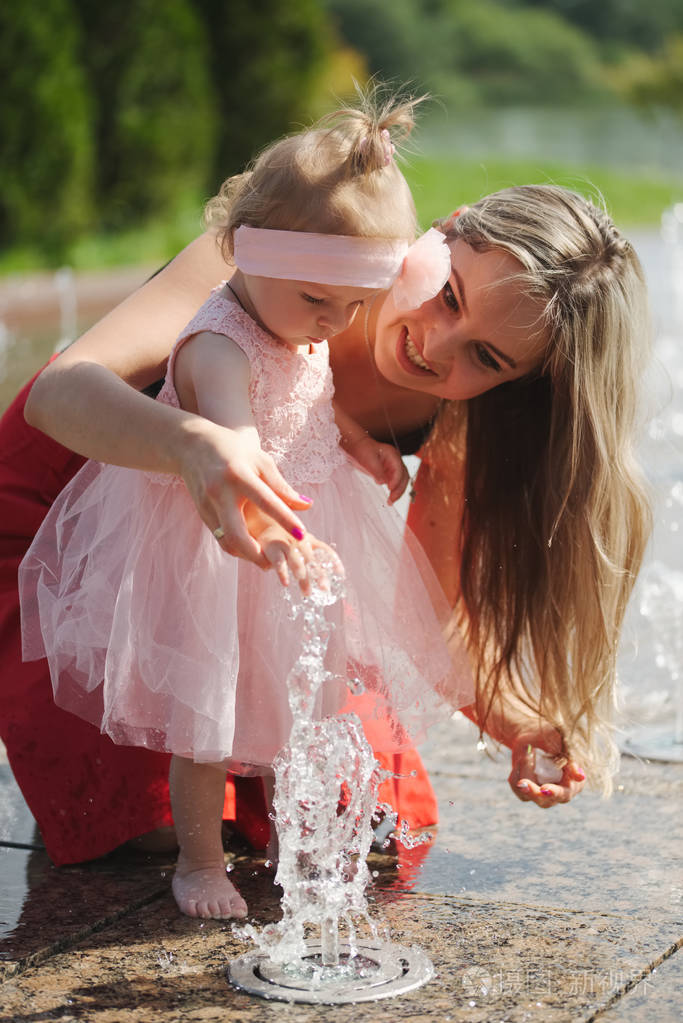 年轻的母亲带着女儿在喷泉
