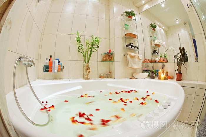 带有按摩浴缸和玫瑰花瓣的暖色调的现代浴室