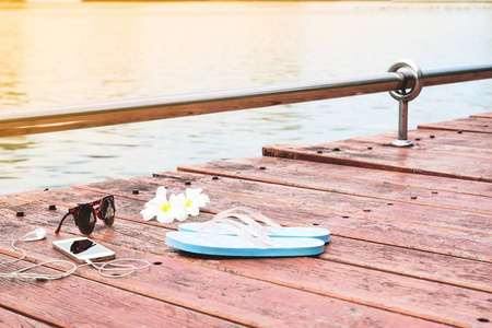 女人配件和智能手机上木阳台附近的湖，夏天和旅行的概念