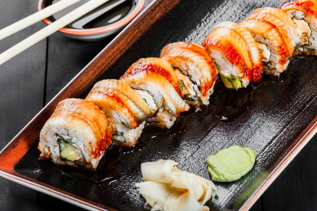 做寿司卷烟熏鳗鱼寿司寿司 黄瓜，牛油果和奶油奶酪上深色木制背景。顶视图。日本料理