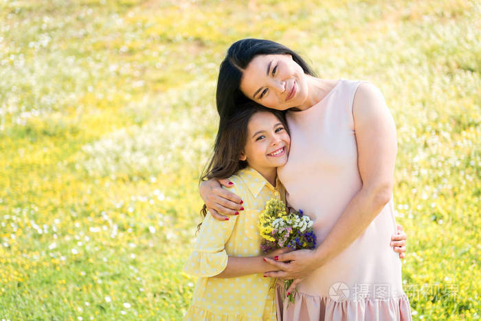 开朗的妈妈和女儿拥抱在草地上