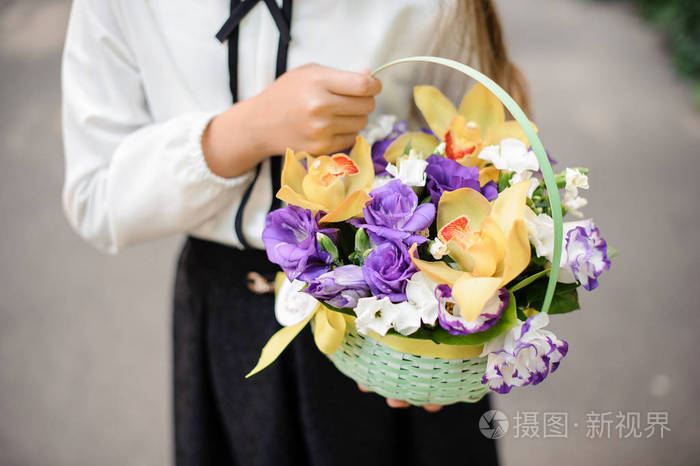 女孩抱着美丽和软柳条篮子里的花