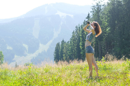 年轻女人看着山上通过双筒望远镜，户外