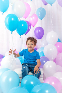 欢乐的色彩缤纷的气球一堆搞笑儿童男孩在他的手中。在白色隔离