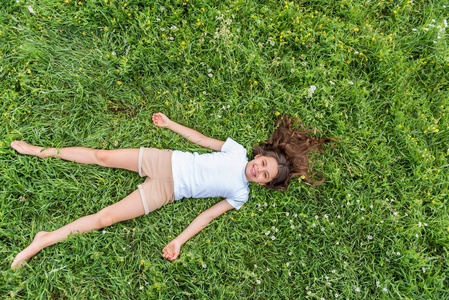 可爱的小女孩在夏天草地上放松