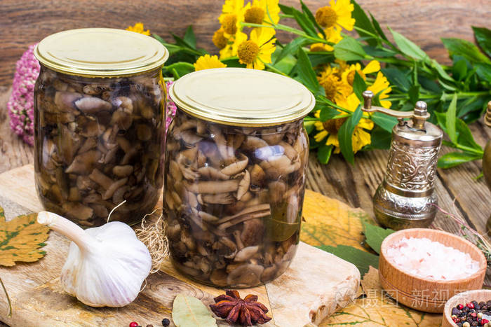 秋天的森林腌制蘑菇在玻璃罐子里盐香料木制的桌子上