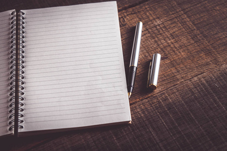 与筛选器效果复古怀旧风格木背景上的书和笔照片