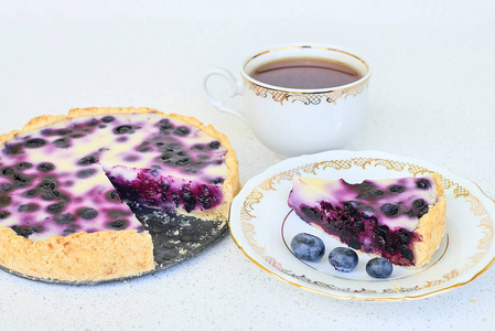 蓝莓馅饼 杯红茶 一块馅饼和三个蓝莓在白色背景上的盘子